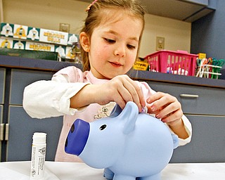 A penny saved is a penny earned as Natalie Tobey 3, puts money in the bank she received from the program - at the Librarys Smart Money program that was presented at Boardman Library by John Yingling