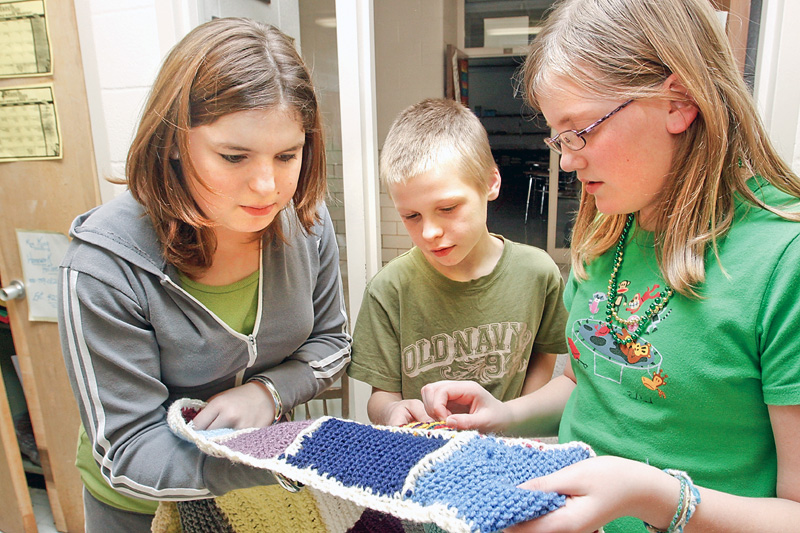 Kristin Boyd (14) Brett Rodgers (12) and Alexis Ramsey (12) look at the different knitted stitch squares made by everyone whose participating in the afterschool program at W.S. Guy Middle School in Liberty.
