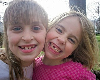 CAITLIN PERRY (left) and AIDAN MCDANEL compare smiles and missing teeth on their street in Poland Township.