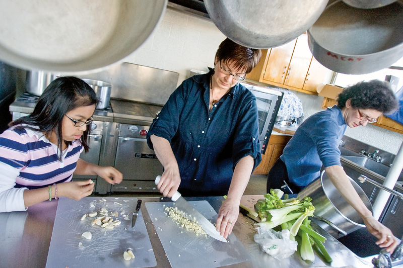 Deana Berman, 12 of Boardman, and Sherri Garver, of Columbiana County, peel garlic while Chaia Beckerman gets water for a stew being prepared at the Ohev Tzekek Synagogue in Youngstown on Wednesday. The stew is being prepared as part of a Passover meal.