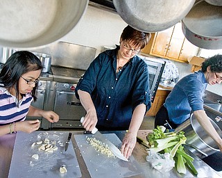 Deana Berman, 12 of Boardman, and Sherri Garver, of Columbiana County, peel garlic while Chaia Beckerman gets water for a stew being prepared at the Ohev Tzekek Synagogue in Youngstown on Wednesday. The stew is being prepared as part of a Passover meal.