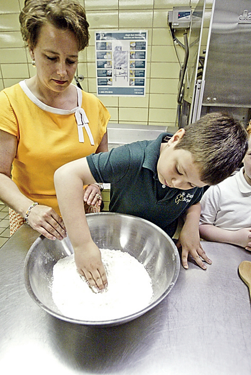 St. Patrick School 2nd grade teacher Mellony Leonard helps student Blake Yendrek mix bread dough at the school 4-27-09. Second graders were making bread for Holy communion. 