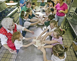 Second graders at St Patrick School in Hubbard participate in a project to make bread for Holy Communion. At left is teachers aid Viola O'Connor.
