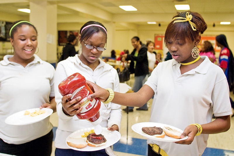 Eighth Graders Charisse Brown (right), and Kiana Bell (center) put catsup on their hamburgers as fellow eighth grader Trayionna Walker watches during a cookout held by the After School Alliance at Volney Rogers Junior High on Thursday afternoon.