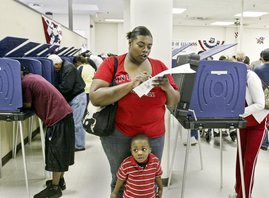 Courtney Sims of Youngstown checks her ballot while voting Monday at the Mahoning County Bd of Elections. Her son Aleander Sims, 3, is in foreground. She was one of thousands of area voters who cast their ballots early. William D. Lewis The Vindicator