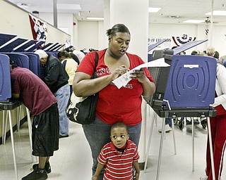 Courtney Sims of Youngstown checks her ballot while voting Monday at the Mahoning County Bd of Elections. Her son Aleander Sims, 3, is in foreground. She was one of thousands of area voters who cast their ballots early. William D. Lewis The Vindicator