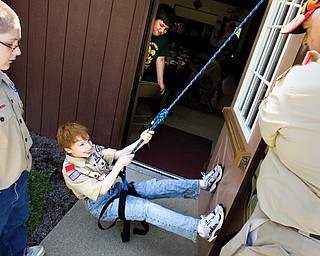 Stephen Scannell, 11, a Tenderfoot with Troop 22 repels down a door as Robert Zedaker, Scoutmaster with Troopp 44, and Kyle O'Brien, 12, a Scout also with Troop 22 looks on during instuction on the climbing merit badge at Camp Stambaugh in Canfield on Saturday afternoon.