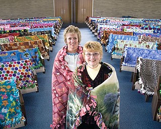 BLESSED BLANKETS: Wanda Marland, foreground, and Diane Wise, coordinators of the Comfort Blanket Ministry at Western Reserve United Methodist Church in Canfield, are wrapped up in two of the 117 blankets made by church members as a special project. Blankets “take their seats” in the sanctuary, where they were blessed.