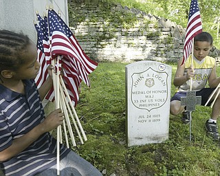 K'emonie Colpetro, 9, places a flag on the grave of Maj. John A. Logan in Oak Hill Cemetery, Youngstown. Looking on is Larenz Rhodes, 8. Both boys are members of a youth group at American Legion Post 732 in Youngstown helping decorate graves at Oak Hill Cemetery . Maj Logan is the son of General John A. Logan who issued General Order 11 at the end of the Civil War resulting in Decoration Day and then Memorial Day.