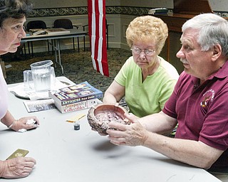 Dahlia Clemen of Liberty, left, looks on as auctioneer Marcel Ulrich of McDonald evaluates an antique ashtray  for her during an event Friday at Shepherd of the Valley in Howland. Next to Ulrich is a friend of Ulrich's Delores Kale of Warren.