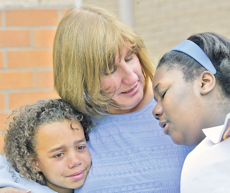 Carole Betz, Willard School Warren counselor, hugs 6th graders De'Shey Staggers, left, and Chaleesa Seawood during a Friday ceremony at the school. Fellow student Lloyd McCoy Jr.,  a 6th grader at the school, was killed in a recent shooting. May 22 was his birthday. Students planted a tree in his honor.