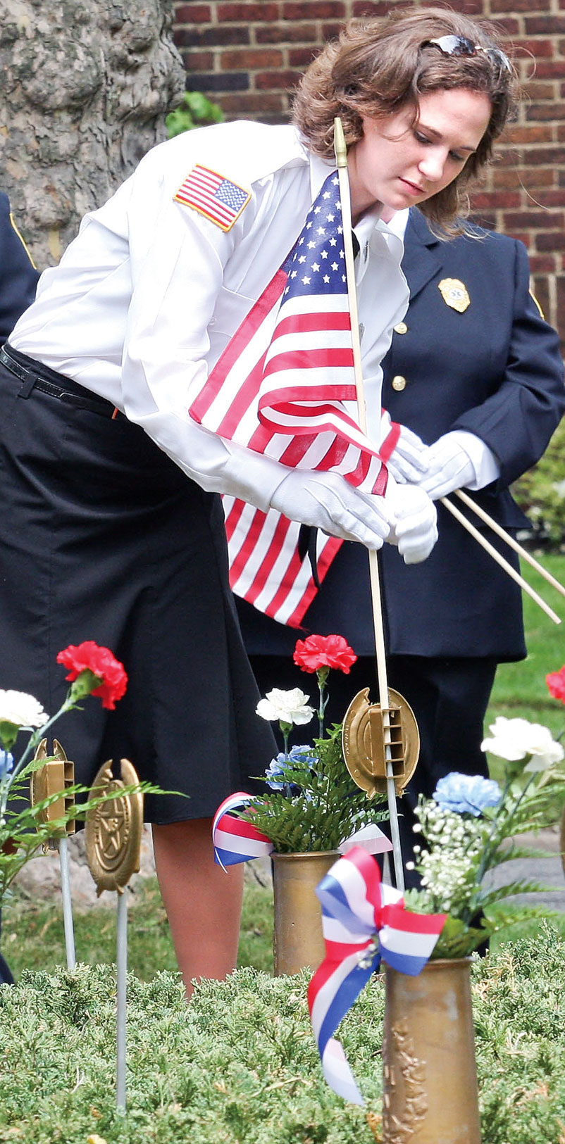 Firefighter/EMT Lee Ann Setser places a flag during the Memorial Day services Sunday afternoon in McDonald.
