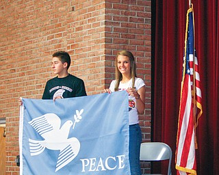 PEACE SIGNS: Above, elementary students in the Team 2 class of Susan McConnell of Robinwood Elementary School use sign language for one of several songs for the U.N. Day event. At right, Korey Johnson, an eighth-grader at Center, shows off the peace pole that was dedicated to Bill Vegh of Liberty, a Holocaust survivor from World War II.