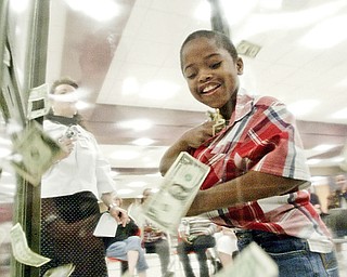 Zion Rushton, kindergarten student at Harding Elementary school stuffs cash into his shirt in the money machine during Friday event at Choffin Career Center. Students in the district with prefect attendance got a chance to grab cash in a money blowing machine.