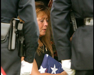 Framed by honor guards Renee Possert holds the flag as Army Chief Warrant Officer S. Blane Hepfner is laid to rest at Hubbard Union Cemetery.