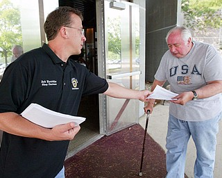 UAW 1112 shop chairman Bob Marstellar passes out information to GM/UAW retiree Larry Ayers of Austintown outside Metroplex Hotel in Liberty Tuesday. More than 1,500 retirees attended the meeting to find out details of health care plan.