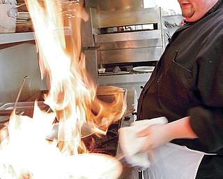 Fourth Street Cafe chef Stephen Grant prepares flaming entree in the kitchen of the Salem eatery Thursday.