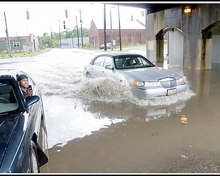 6.17.2009
Damon Washington (left), of Youngstown, sits in his car beneath the B&O Railroad bridge on Marshall St. in front of its intersection with Oak Hill Ave as another motorist passes him by braving the flooding water that left his car unable to start. After a passerby unsuccessfully tried to help jump the waterlogged car, Washington was able to reach family and friends on a cell phone and they were able to come and tow the car away where it could dry out.
Photo by: Geoffrey Hauschild
