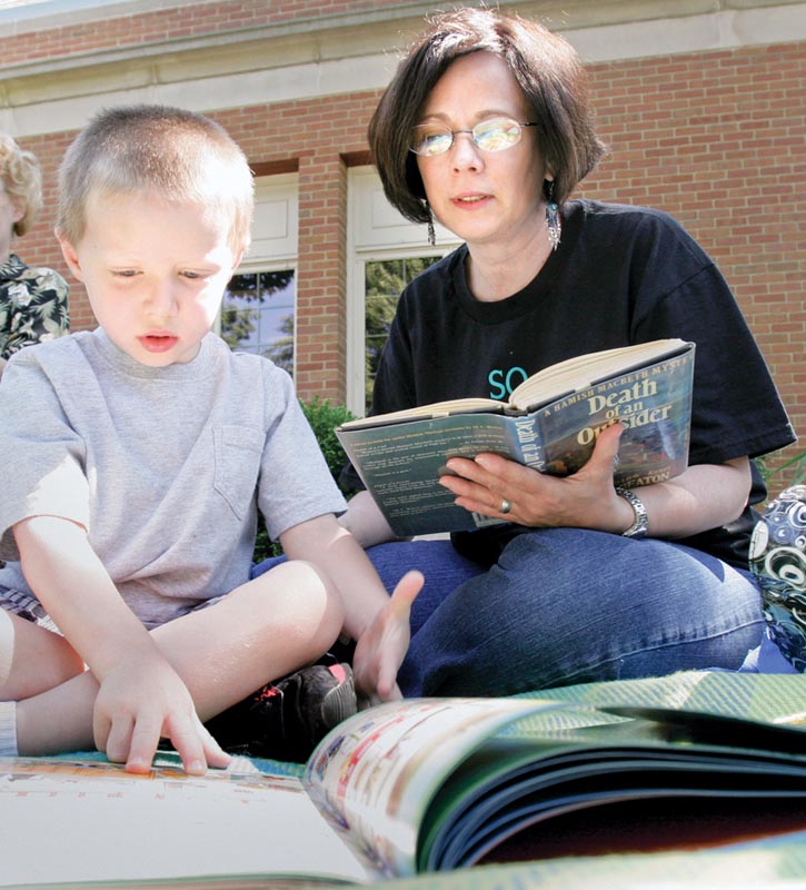 Carol Genova and her grandson Colin Genova, 5, of Niles, participate in a read-in at the main library in Warren Monday to bring attention to proposed library funding cuts.