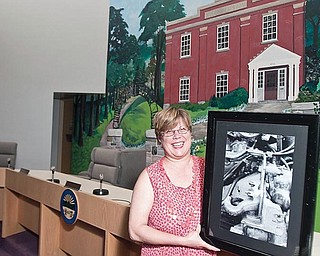 framed work: Kathryn Infante of Liberty displays one of her photographs, the undercarriage of a truck, which has been featured in the display of artwork by residents at the township administration building, 1315 Church Hill-Hubbard Road. She’s in the meeting room at the administration building. The current display shows peonies by Infante and acrylics featuring various subjects by Tim Micklas.
