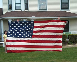 Sue, Katie and Mike Centorame of Canfield display the flag they inherited from their uncle and aunt, Steve and Doris Colucci of Youngstown. It hung over their front porch for the Bicentennial and appeared in The Vindicator at that time.