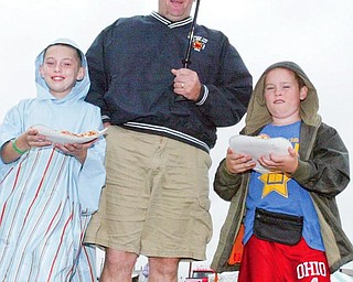 Tal Lewis of Champion and his sons Thomas, 10, left, and Caleb, 8, keep dry while visiting the Trumbull County Fair Thursday.