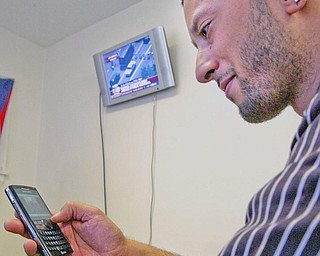 Barber James Kershaw watches Michael Jackson's funeral on his phone as it is broadcast on TV in the background at Legends Barbershop in Youngstown.