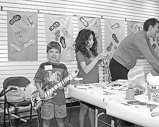 Special to The Vindicator
CRAFTY KIDS: Trumbull Art Gallery in Warren was the setting for Summerfest 2009, which concluded July 1 with a parade and display of crafts at Courthouse Square. During the two-week program, children had the opportunity to create unique arts and crafts. In the top photo, Dante Byrne of Girard displays the guitar he made, while his sister, Francesca Byrne, concentrates on her bead-stringing project. In the bottom photo, Lauren Ulrich of Toledo, at left, and Lauren Kromer of Howland show off the guitars and one-of-a-kind hats they made during the Summerfest. At right in both pictures is Lauren’s mother, Stephanie Kromer, who assisted the young crafters.