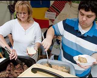 7.11.2009
Maggie Craciun, of Austintown, and Eric Shehadi, of McDonald, serve up Romanian foods including Mititei, a form of sausage, and stuffed cabbage while working in Holy Trinity Romanian Orhodox Church's booth on YSU's campus during the YSU Festival of the Arts on Saturday afternoon.
Geoffrey Hauschild