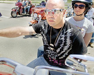 PAYING TRIBUTE: Ray Kirchner of Youngstown, an officer with the Mahoning County Sheriff's Department and Mill Creek MetroParks, wears black tape over his badge in a tribute to fallen officers while sitting on his motorcycle with his wife, Carrie. They were outside the Covelli Center in downtown Youngstown before the Fallen Officers Memorial Run on Sunday.