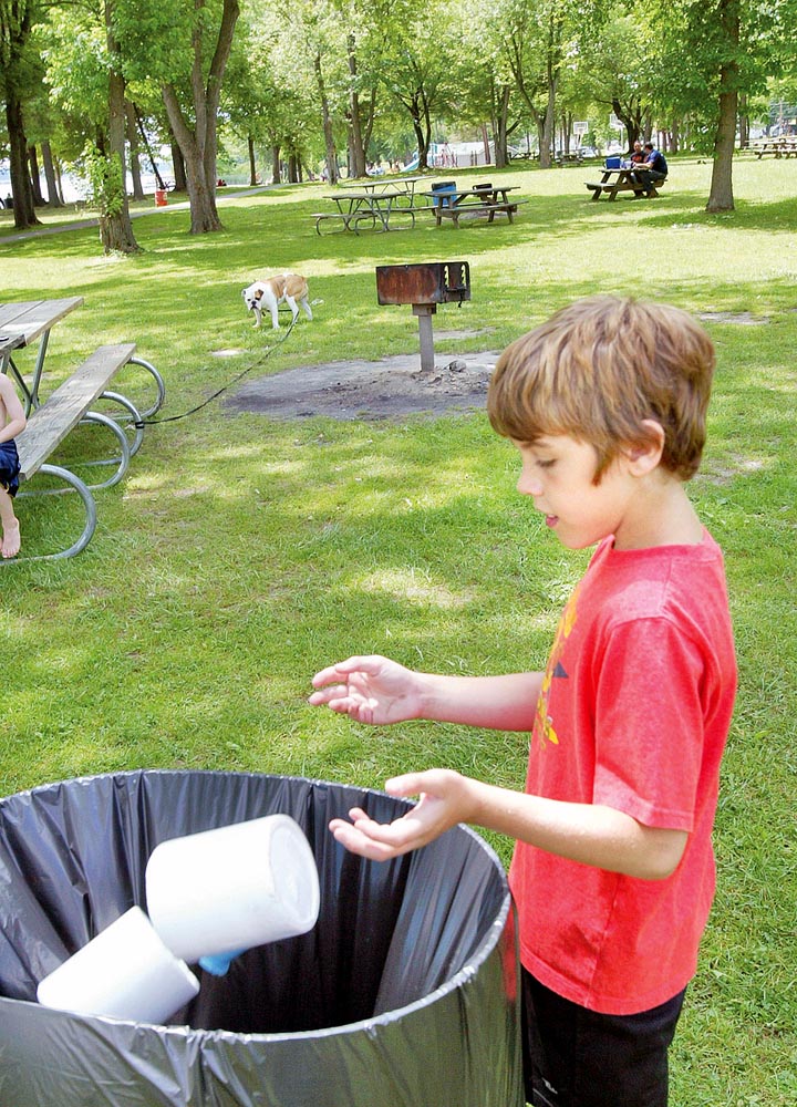 Coulton Lockner, 12, of Lake Milton, tosses trash into a barrel at Lake Milton State Park. Lake Milton is one of the area parks not participating in the "Carry In Carry Out" program. 