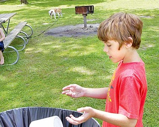 Coulton Lockner, 12, of Lake Milton, tosses trash into a barrel at Lake Milton State Park. Lake Milton is one of the area parks not participating in the "Carry In Carry Out" program.