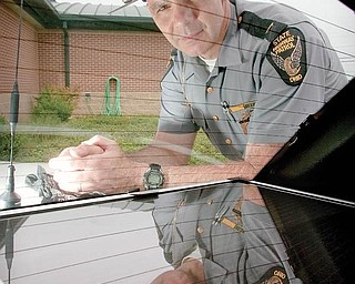 Lt. Mike Orosz, of Boardman, stands above a solar panel in the back of his patrol vehicle while at the State Highway Patrol Post in Lisbon on Wednesday afternoon. Solar Panels have been installed in order to lengthen battery life.