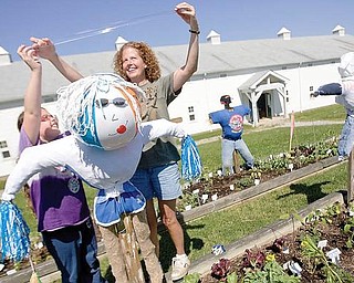 Erica Shirilla, age 10, and her mother, Andrea Shirilla, both of Boardman, put the final pieces of tape on Dolly, a scarecrow named for her resemblence to the country singer Dolly Parton, that overlooks their garden plot at the Mill Creek MetroPark Farm in Canfield on Wednesday morning. Erica, who attends the children's gardening program every Wednesday has also talked her parents into allowing her to have a garden at home. "I'm independent," says Erica whose favorite vegetable to grow is onions because she likes them in salsa, "I've never been to a place where you can have your own garden and you can do it all yourself." "Every Wednesday, I get to harvest and get food," says Erica, "Its fun."