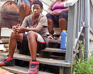 Lucky and his owners Benjamin Roberts, 12, Unique Roberts, 14, and their mother, Desiree Johnson, sit on the back stairs of their Kenmore Street home. The family speaks out about their brush with the Youngstown Task Force.