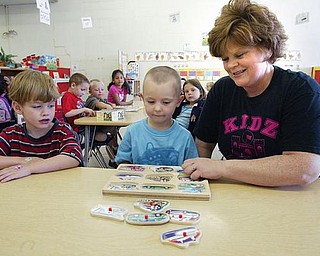 EARLY LEARNING: Theresa Herrick, co-owner of the Kidz Kastle preschool in Girard, helps pupils, Christopher Glunt, 5, left, and Mason Day, 3, with a puzzle. Herrick lamented the abolition of the state’s Early Learning Initiative program due to budget constraints.