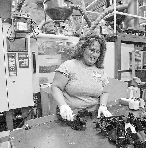 Venture Plastics employee Joanne Streets examines automotive brackets produced at the Newton Falls plant. The company is celebrating 40 years in business.