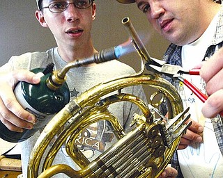 Derrick Kittle, left, and Franklin Stout, both students at Youngstown State University, work on a French horn during an instrument-repair class in Bliss Hall on campus. Students learned to solder instruments Wednesday.