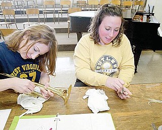 Krista Ferry, left, and Shanna Kelly clean the areas they plan to solder back together on a trumpet in the instrument-repair class. 