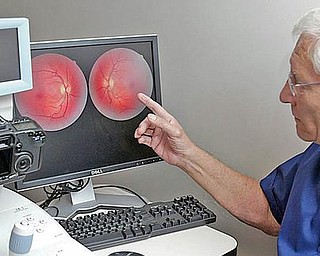 Dr. John J. Guerriero demonstrates a retinal camera that makes images of the interior of patients eyes and enables the optometrist to view blood vessels and determine if there is damage from conditions such as diabetes and macular degeneration. Unlike the old days, when the doctor had to remember from examination to examination, the images of the eye can be kept from year to year to make comparisons to determine if a condition has changed.
