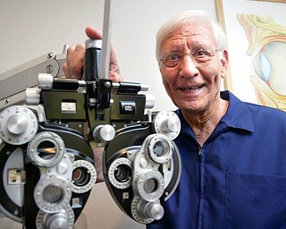 Optometrist Dr. John J. Guerriero of Boardman stands next to a phoropter, an instrument used during eye examinations to determine eyeglass prescriptions. Dr. Guerriero has been in practice 50 years this month, starting in 1959 in Warren, and opening an office on Canfield Road in Cornersburg two years later.