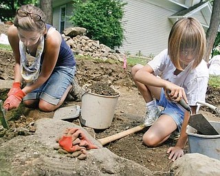 DIRTY WORK: Youngstown State University student Carla White, left, of McDonald, is assisted on the dig by 10-year-old Marissa Cashbaugh during a learning exercise on the site of the former courthouse. An advanced archeology class at YSU participated in the dig.