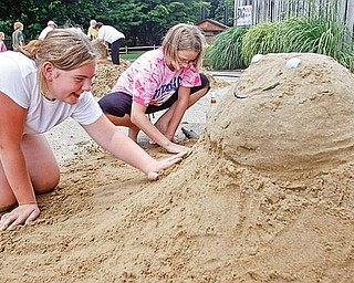 PATTING IT DOWN: Twelve-year-olds Rachel Zedaker and Ryann Brown of Hubbard work on The Turtle Sunday  competing in a sand sculpture contest during Mill Creek MetroParks’s annual Sunfest. Rachel’s and Ryann’s  work of art took first place in the Children’s Division.