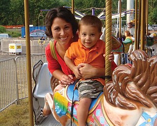 Anthony Coppola of Union, Ky., and his mom, Colleen, ride on the carousel at the Mount Carmel Festival in Lowellville.