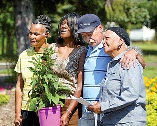 Willie Mae Johnson, far right, stands with her daughters, Sandra and Vickie, and son, William, as the family receives the Good Neighbor Award, a plant and gardening gloves Monday from Lien Forward Ohio. The Johnsons have been cleaning and landscaping vacant lots at Norwood Avenue and Wirt Street for the past three years.