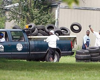 City workers remove tires collected and stacked as the Give the Children a Chance Choir and people from MCTA cleared trees removed tires and debris mowed and planted gardens on Truesdale Avenue.