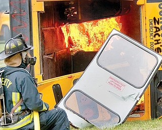 TRAINING: Liberty firefighter Chuck Wise watches the flames in an old school bus set afire as part of a training exercise. Firefighters learned where and how to cut into the reinforced buses. Newer buses have roof hatches and emergency window exits, which help in evacuations. 

