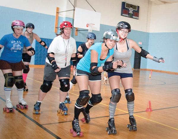 Mandy Tucker (second from right) squeezes past Natalie Clark (right), who tries to block her progress during a roller derby practice by the Little Steel Derby Girls at the Boys and Girls Club of Youngstown on Sunday evening. 