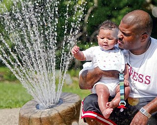 HEAT RELIEF: Anthony Hartsfield of Youngstown and his son Jayden, 6 months, cool off in a fountain at Mill Creek Park. Temperatures reached 90 degrees Monday when the Hartsfields were enjoying the fountain but should return to the low 80s today.