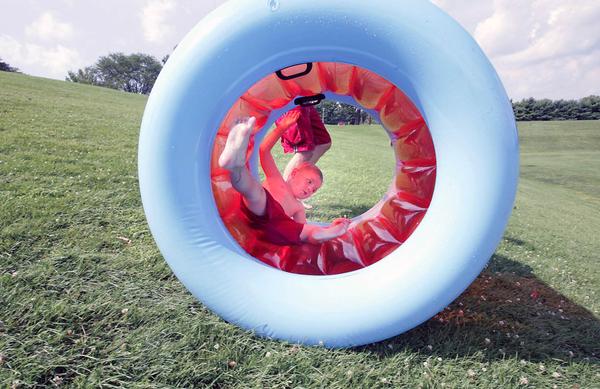 ON A ROLL: Isaiah Walter, 3, rolls down a hill in an inflatable tube at Mill Creek Park in Youngstown Monday. His father, Daniel Walter, of Youngstown, runs alongside the tube. With temperatures in the 90s Monday, Mill Creek Park seemed to be a popular place to beat the heat.